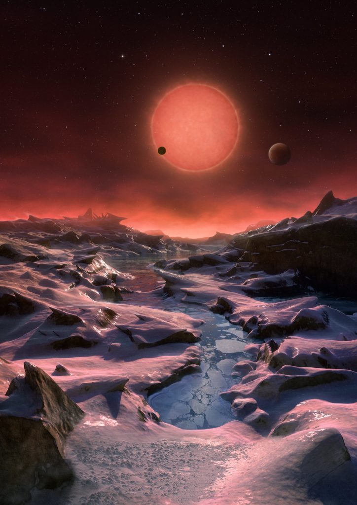 This artist’s impression shows an imagined view from the surface one of the three planets orbiting an ultracool dwarf star just 40 light-years from Earth that were discovered using the TRAPPIST telescope at ESO’s La Silla Observatory. These worlds have sizes and temperatures similar to those of Venus and Earth and are the best targets found so far for the search for life outside the Solar System. They are the first planets ever discovered around such a tiny and dim star. In this view one of the inner planets is seen in transit across the disc of its tiny and dim parent star.