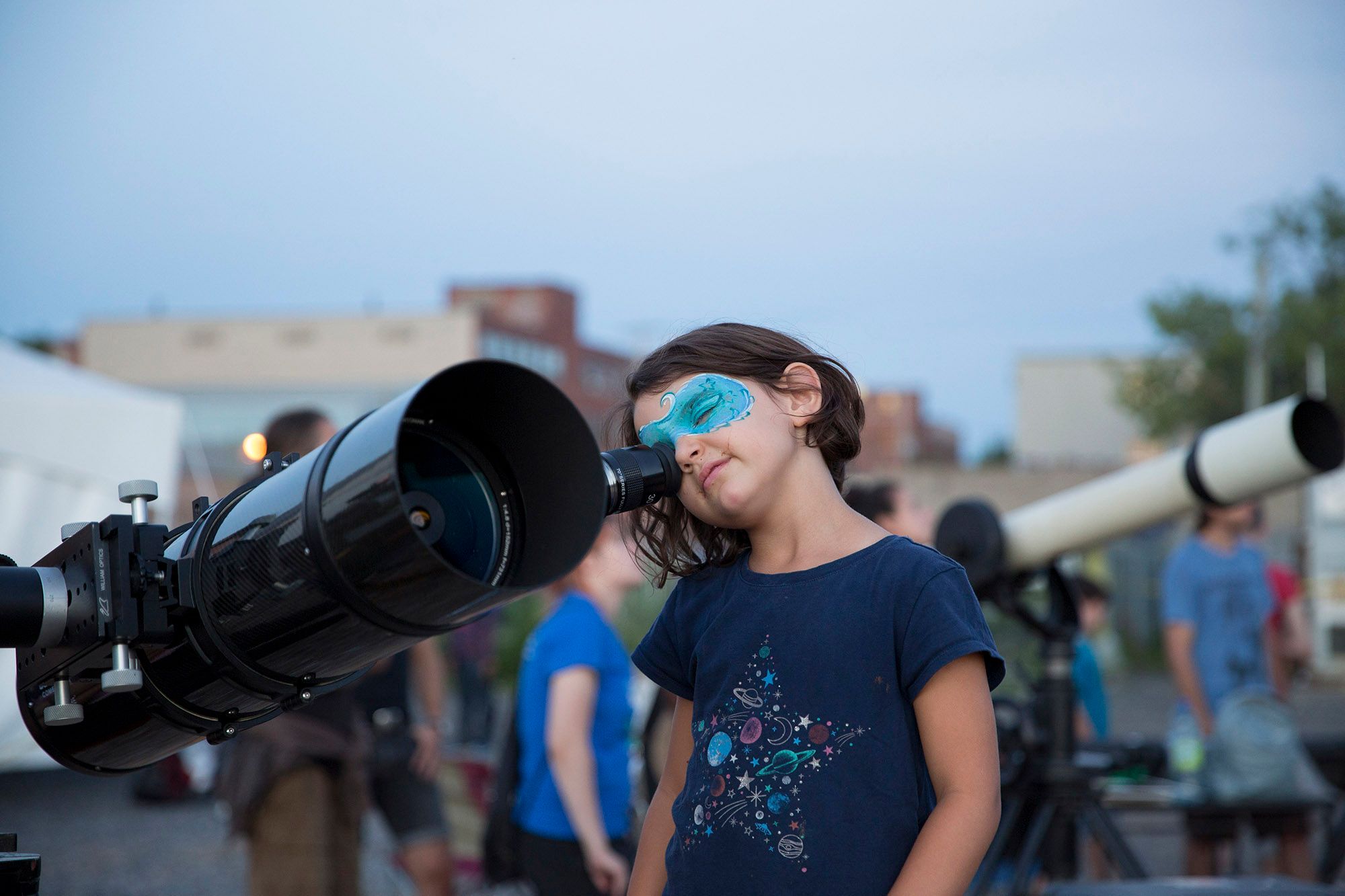 An image of a child looking through a telescope at the 2018 astroMIL event. (Credit: M. Boyce)